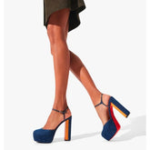 Blue high-heeled shoes with colorful soles worn by a person on a white background